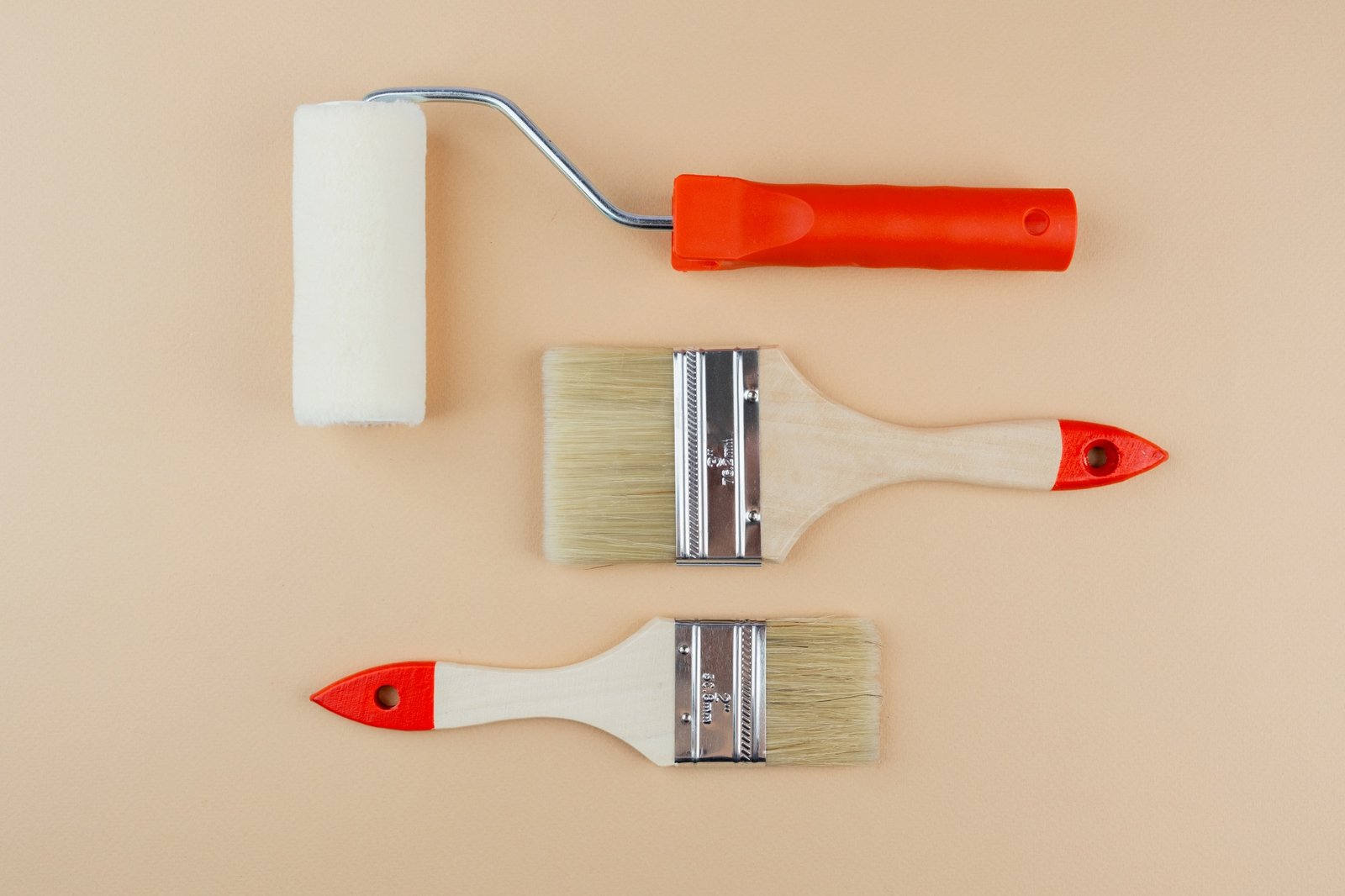 Paint roller and brushes on beige background for DIY renovation and home improvement concept